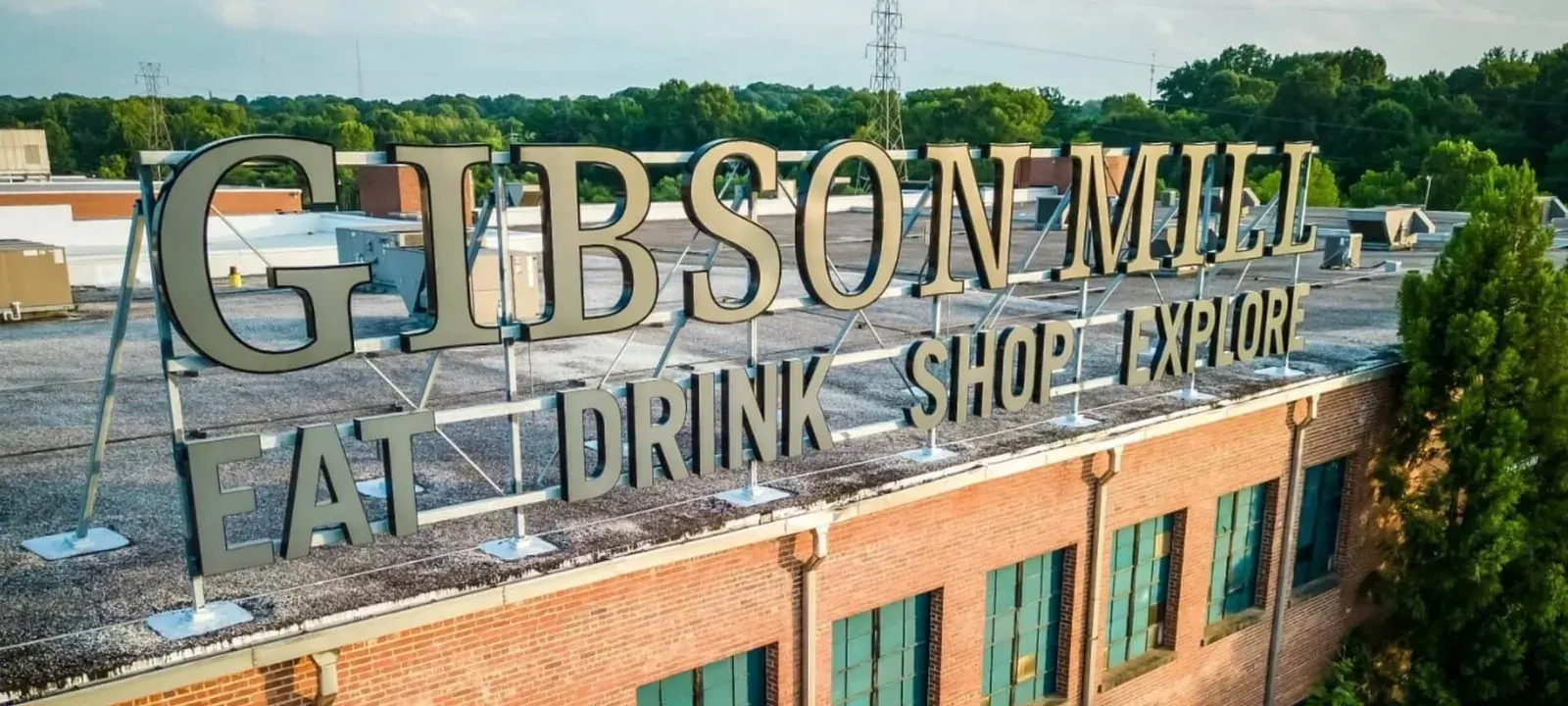 The historic Gibson Mill rooftop sign above the brick mill buildings